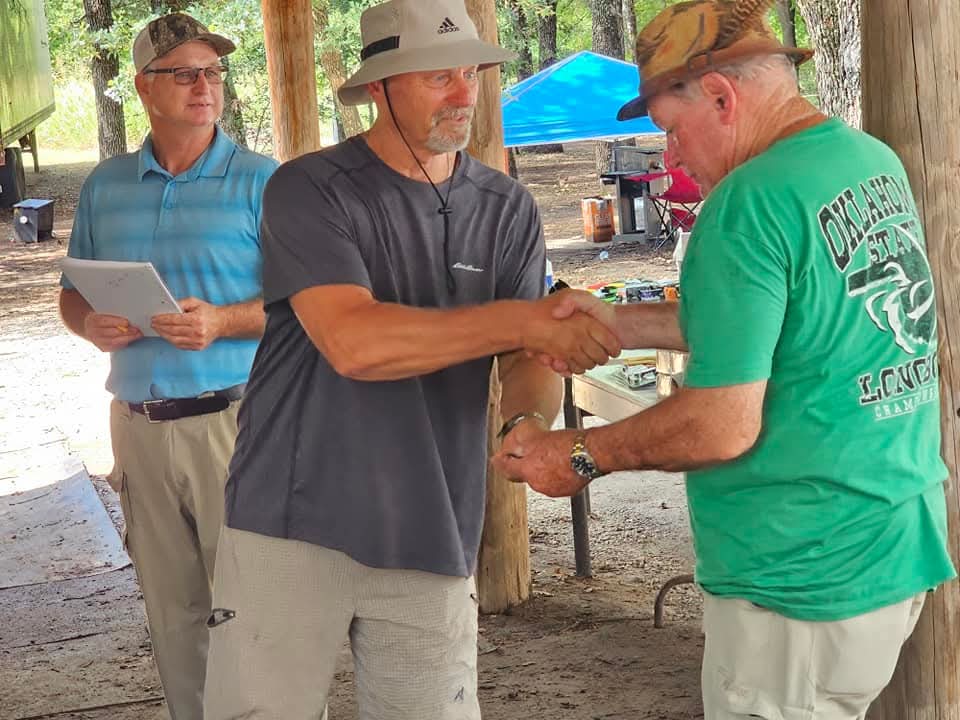 Two archers shaking hands during a shoot award presentation