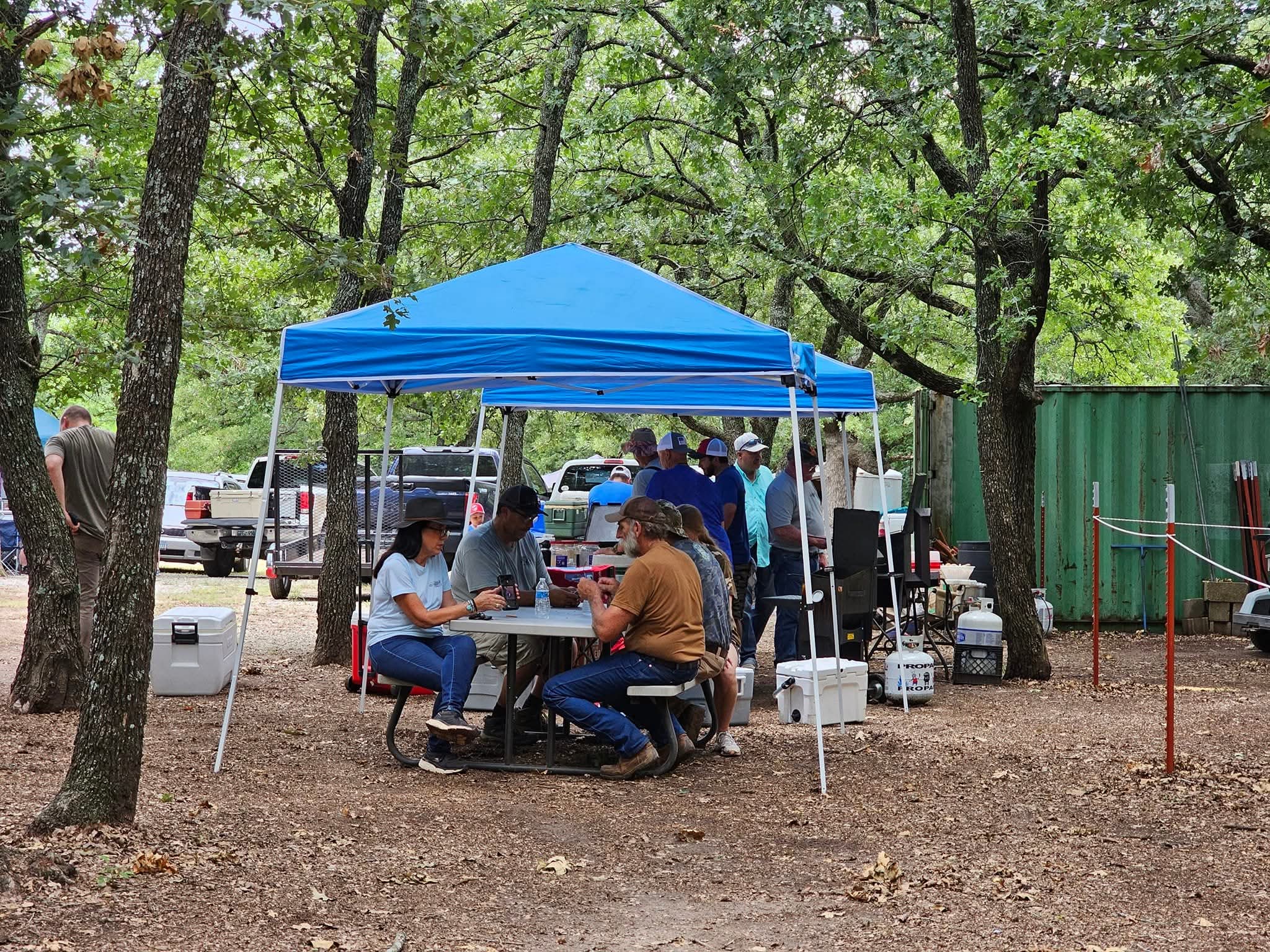 Archers gathering beneath blue canopies during a club shoot